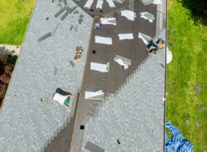 Roofer working on replacement asphalt shingle roof construction